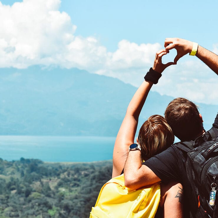 couple-in-the-mountains-making-a-heart-with-their-hands