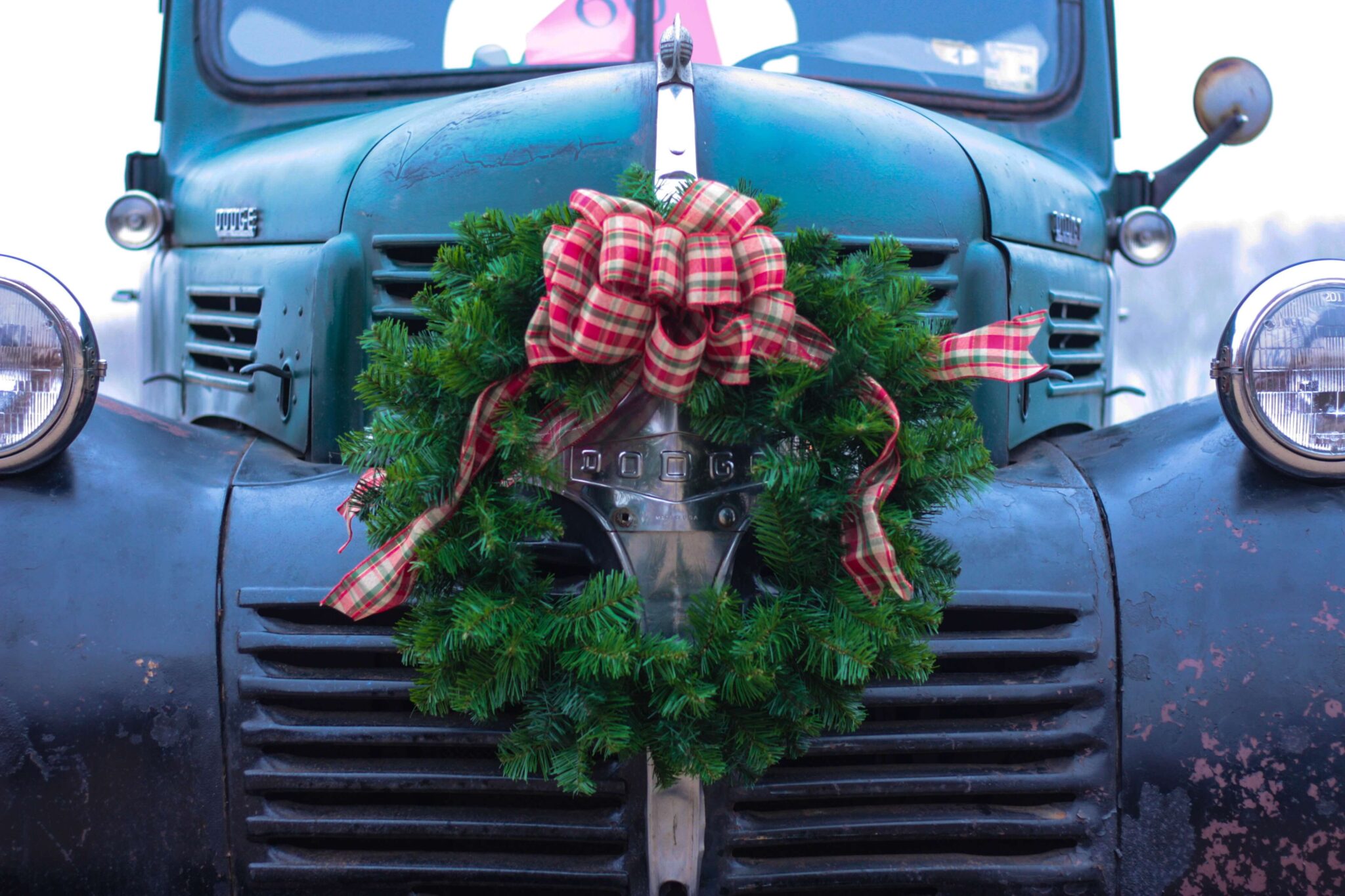 Wreath with red bow on the front of old-fashioned car.